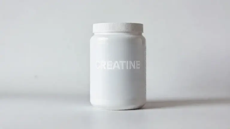 Pote de creatina em pó totalmente sem marca sobre uma superfície elegante, ilustrando os benefícios do suplemento para o corpo feminino.