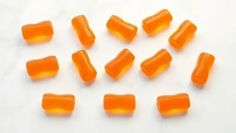 Gomas de creatina caseiras perfeitamente moldadas e coloridas, dispostas de forma organizada sobre uma superfície de mármore branco, prontas para consumo.